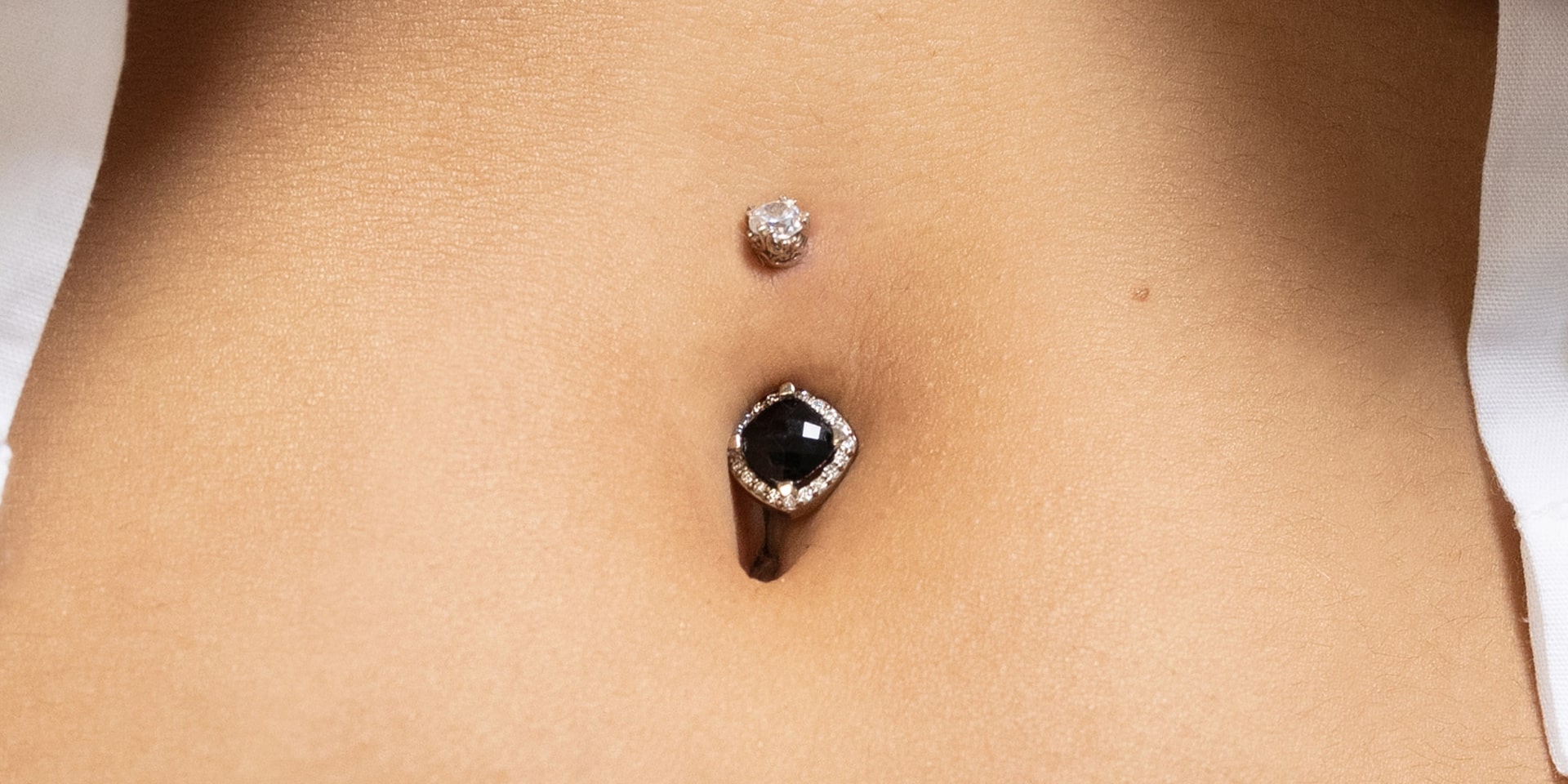 Close-up view of a cartilage piercing and a naval piercing